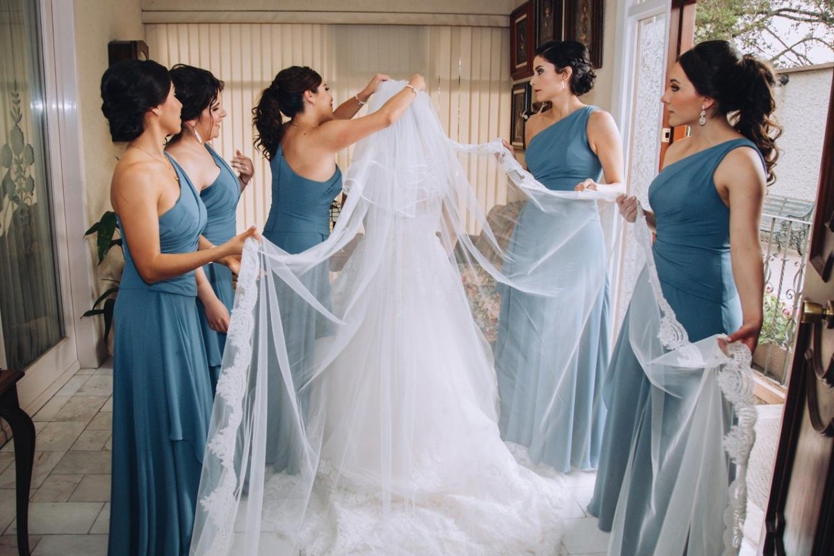 Bridesmaids holding bride veil