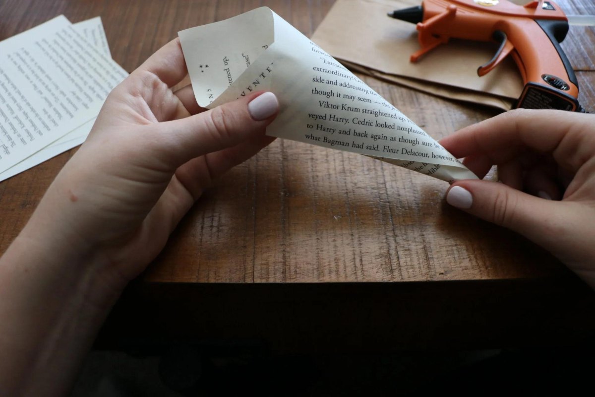 Hands folding a book page cone