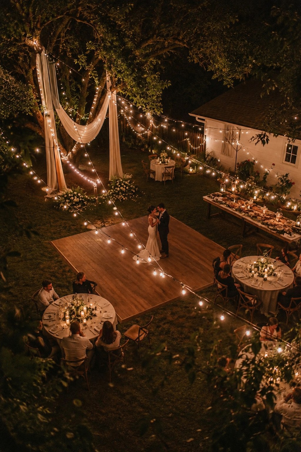 Aerial view of a first dance on a fitted dance floor at an intimate backyard wedding reception.