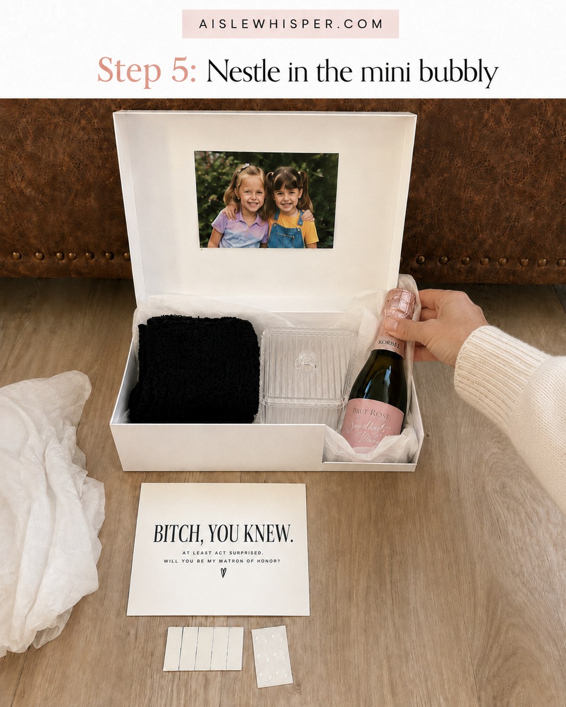 Mini bottle of sparkling rosé being tucked into the corner of the gift box